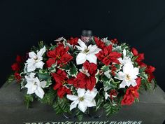 red and white poinsettis are arranged in a vase on a table top