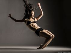 a woman in black and white is dancing with her hair flying through the air,