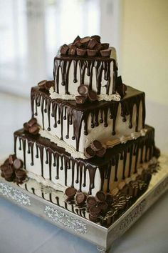 a triple layer cake with chocolate drizzles on top and white icing