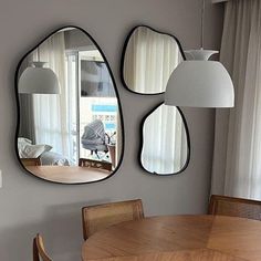 three mirrors hanging on the wall above a dining room table