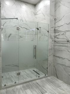 a walk in shower sitting next to a white tiled wall and floor with glass doors