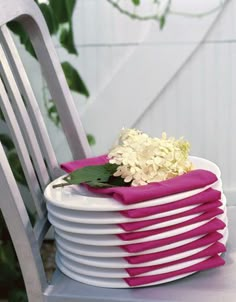 a stack of plates with flowers on them sitting on a table next to a chair