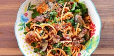 a bowl filled with pasta and vegetables on top of a wooden table