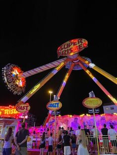 a carnival ride at night with people standing around it