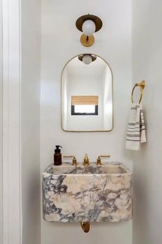 a bathroom with a marble sink and gold faucet