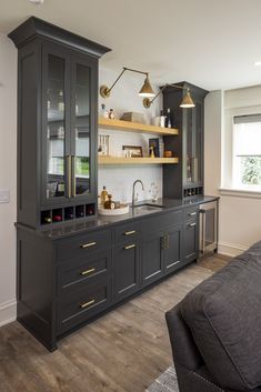 a kitchen with gray cabinets and gold accents on the counter tops, along with a black couch