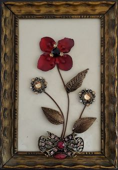 a red flower is in a gold frame