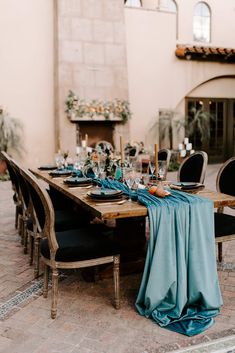 a dining table set with blue linens and place settings