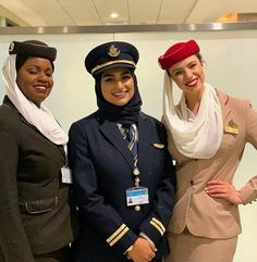 three women in airline uniforms standing next to each other with one woman wearing a headscarf