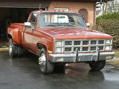 an orange pick up truck parked in front of a garage