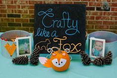 a table topped with pictures and pine cones next to a sign that says crafty like a fox