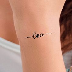 a woman's arm with a tattoo that says love and a dog paw on it