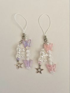 two small charms with butterflies and pearls are hanging from the earwires on a white background