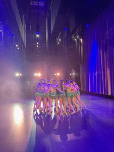 a group of women standing on top of a wooden floor in front of a stage