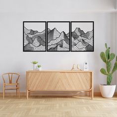 three black and white paintings on the wall above a wooden dresser in a living room