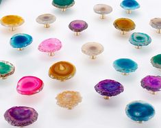 an assortment of colorful glass knobs on a white surface