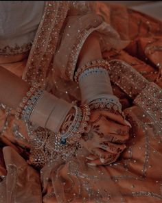 a woman in a wedding dress holding her hands with bracelets on the other hand