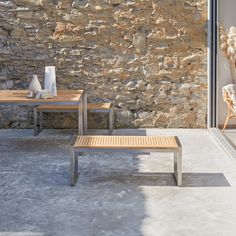 two wooden benches sitting next to each other near a stone wall and glass doored window