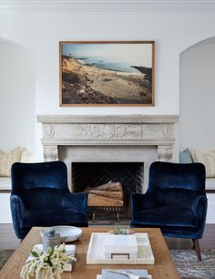 a living room with two blue chairs and a fireplace