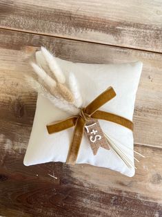 a white pillow with a brown ribbon tied around it and a monogrammed tag on the front