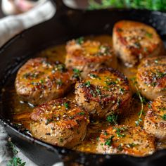 some meat is cooking in a skillet on the table with parsley around it