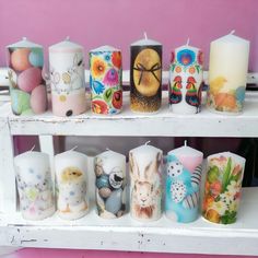 many different types of candles on a shelf with flowers and birds painted all over them