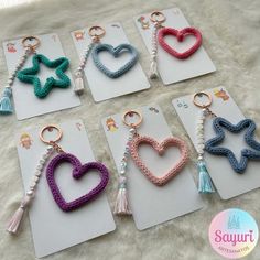 six key chains with hearts and tassels attached to them on a white furnishing