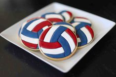 decorated cookies on a plate with red, white and blue stripes in the shape of volleyball balls