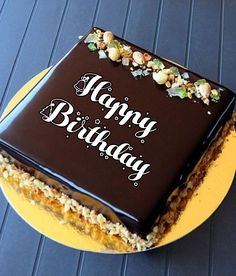 a chocolate birthday cake with the words happy birthday on it sitting on a yellow plate