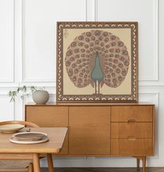 a peacock painting on the wall above a wooden table