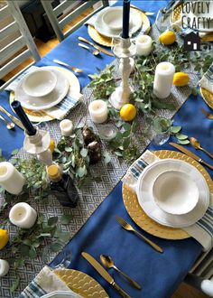 the table is set with plates, silverware and yellow napkins on blue cloth