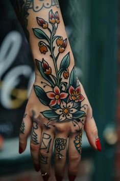 a woman's hand with tattoos and flowers on it