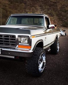 a white truck parked on top of a dirt road next to a motorbike