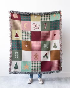 a woman is holding up a blanket that has christmas decorations on it and the words peace, love, joy