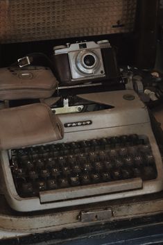 an old fashioned typewriter sitting on top of a table next to a bag and camera