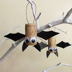 two bats hanging from the branches of a tree with eyes and noses painted on them