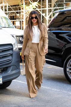 a woman walking down the street in a tan suit