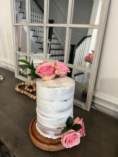 there is a white cake with pink flowers on the table next to it and a mirror in the background