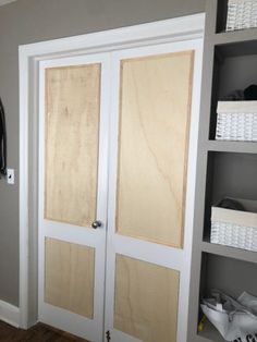 two white doors are open in a room with baskets on the wall and shelves behind them