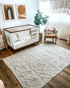 a baby's room with a crib, rocking chair and rug on the floor