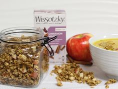 a bowl of granola next to an apple and some cereal in a glass jar