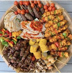 a platter filled with skewered meats, vegetables and other food items