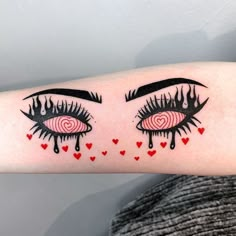 a woman's arm with an eye tattoo and hearts on the inside of it