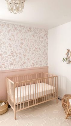 a baby's room with a crib, wicker basket and wallpaper