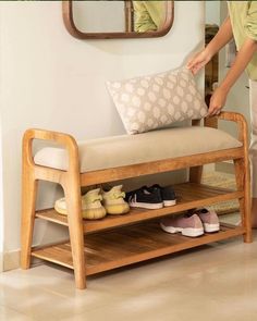 a person standing next to a wooden bench with shoes on it and a mirror in the background