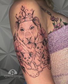 a woman's arm with a lion and two cubs tattoo on her left shoulder