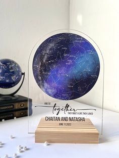 a glass globe with the names of stars on it and a wooden base next to some books