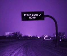 a street sign that says it's a lonely road in front of a purple sky