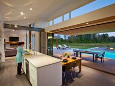 a woman standing in a kitchen next to a pool