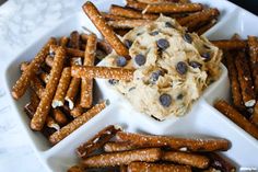 a white plate topped with cookies and pretzels next to a bowl of dip